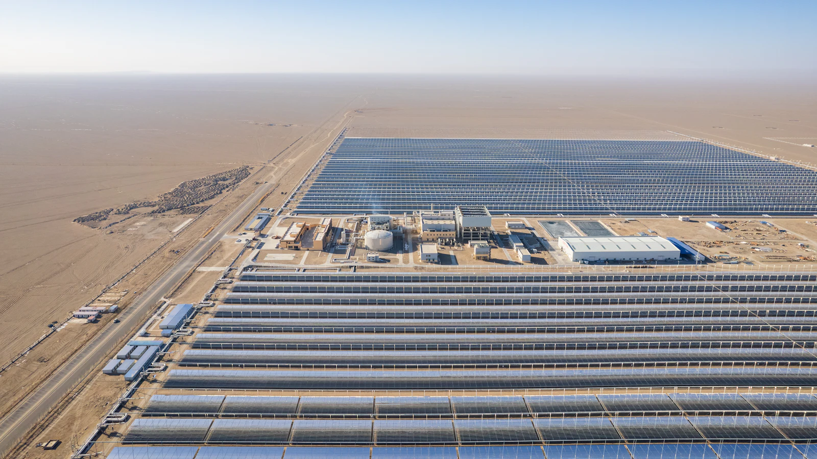 Vista aérea de uma usina solar de grande porte, com fileiras de painéis fotovoltaicos