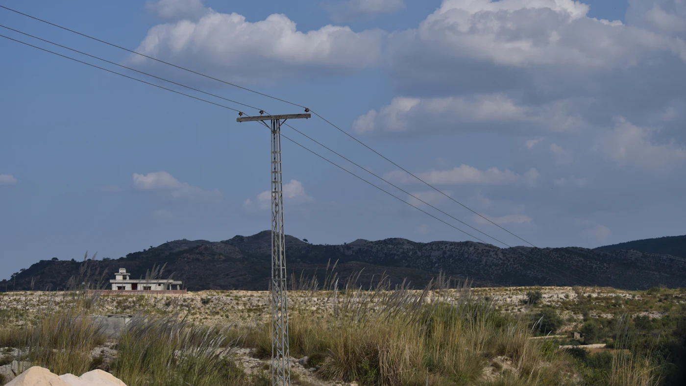 Linhas de transmissão de alta tensão cruzando uma paisagem seca e montanhosa