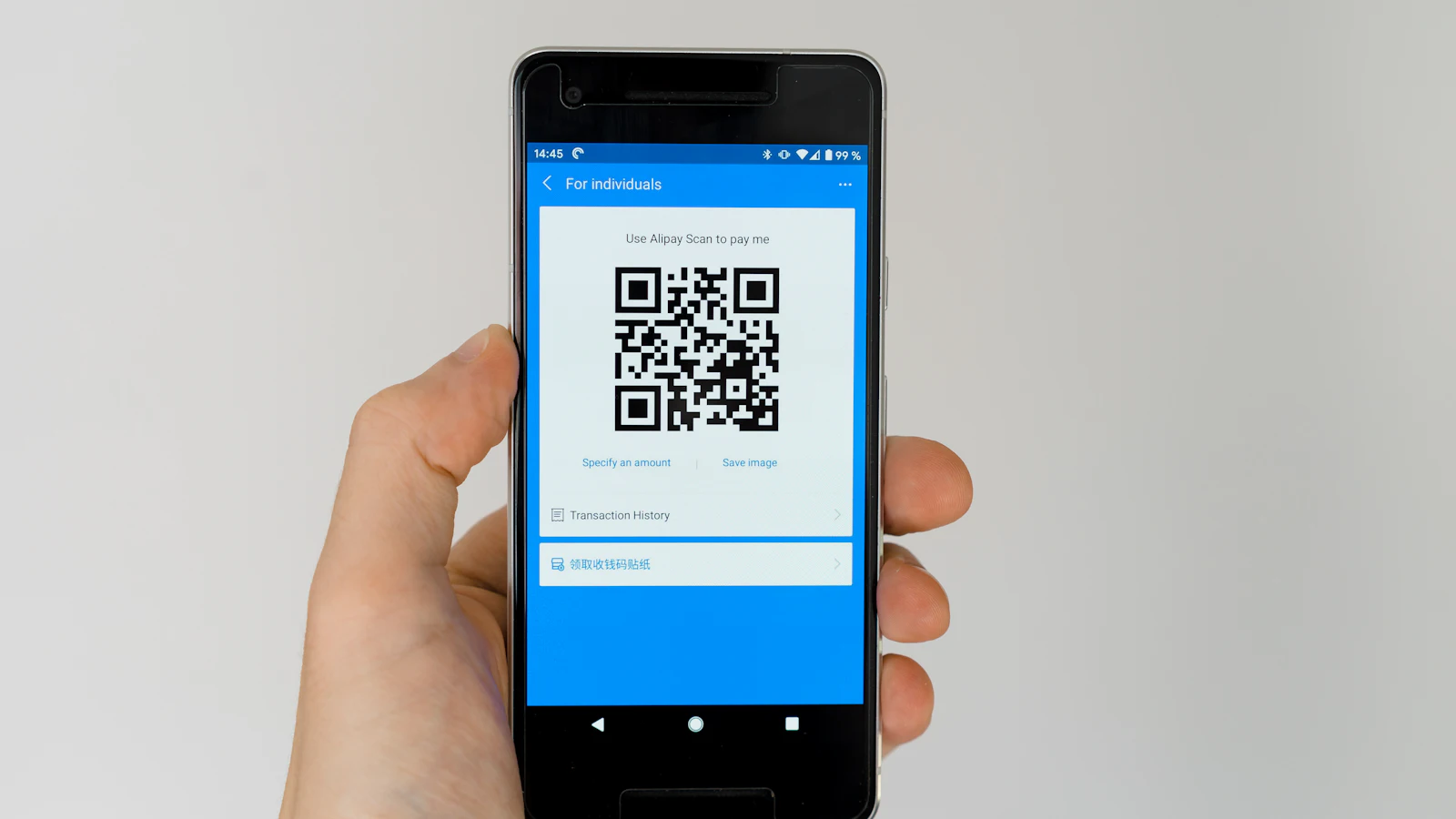 Mão segurando um smartphone que exibe um QR Code de pagamento na tela