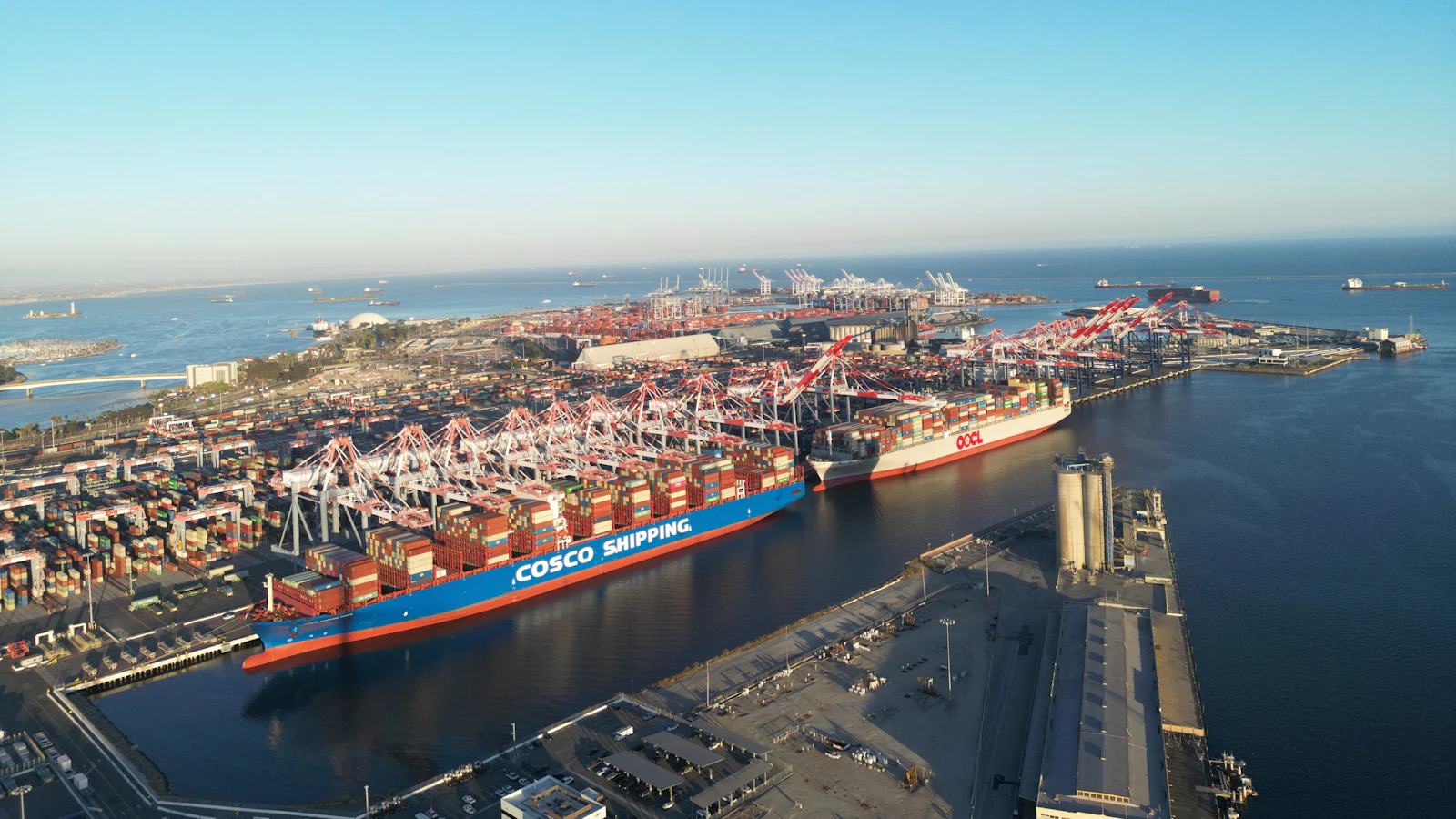 Vista aérea de um terminal de contêineres com navios atracados e guindastes pórtico